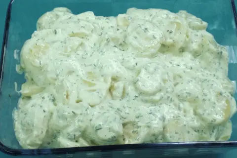 Cremiger Kartoffelsalat mit Kräutern und einem Hauch Balsamico, serviert in einer Glasform.