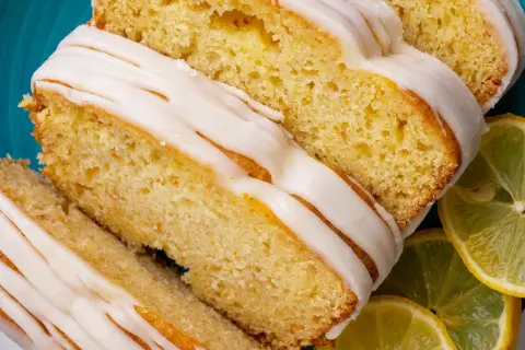 Saftiger zitronenkuchen mit Joghurt, überzogen mit süßer Glasur und garniert mit frischen Zitronenscheiben.