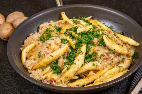 Herzhaftes Gericht mit Spätzle und Sauerkraut, garniert mit Petersilie. Ein tolles Sauerkraut Rezept für Genießer.