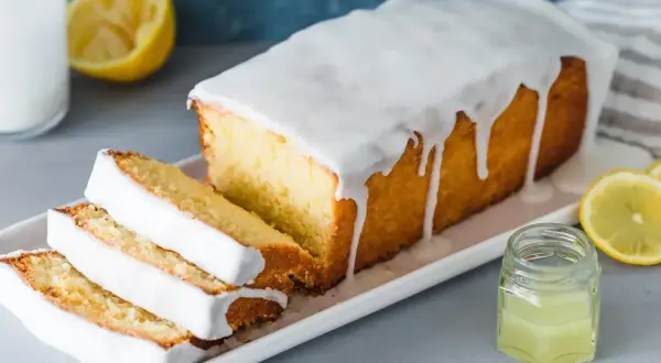 Saftiger Zitronenkuchen mit Zuckerguss, perfekt für ein einfaches zitronenkuchen rezept. Serviert mit frischen Zitronenscheiben.