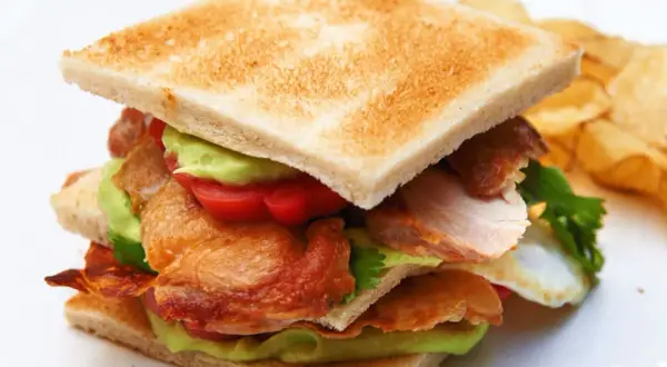 Ein saftiges Club Sandwich Rezept mit Hähnchen, Avocado, Tomaten und knusprigem Speck. Dazu Kartoffelchips.