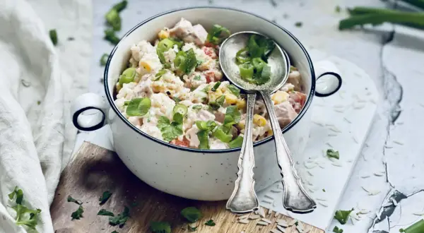 Ein cremiger Reis-Salat mit Hähnchen, Mais und Tomaten, garniert mit Frühlingszwiebeln und Petersilie. Perfekt für ein leichtes Mittagessen.