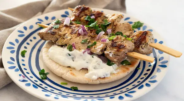Saftige Hähnchen-Souvlaki-Spieße auf Pitabrot mit Tzatziki und roten Zwiebeln. Ein köstliches Souvlaki Rezept für den Sommer.