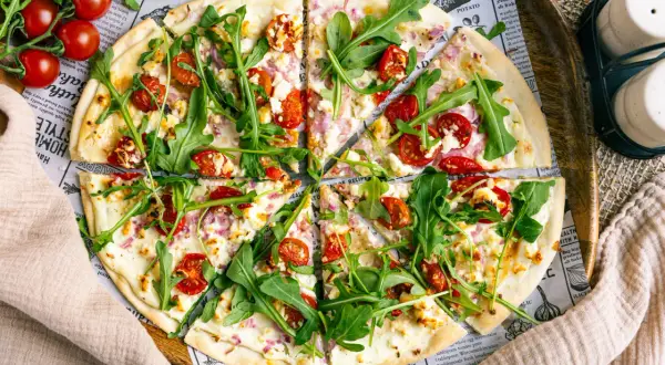 Ein köstlicher flammkuchen vegetarisch mit Kirschtomaten, Rucola und Ziegenkäse auf dünnem Teig.