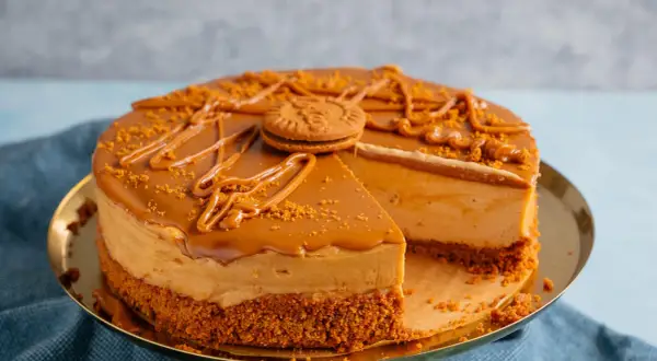 Ein köstlicher Lotus Kuchen mit Mascarpone, dekoriert mit Karamell und Kekskrümeln. Ein Stück fehlt bereits.