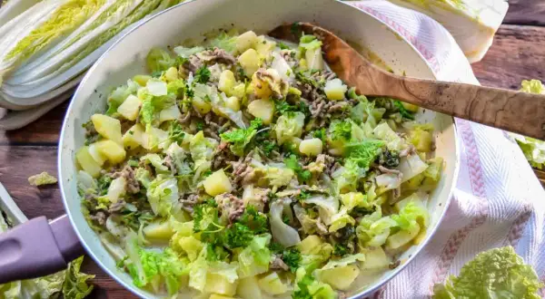 Herzhaftes Chinakohl-Gericht mit Hackfleisch und Kartoffeln in einer Pfanne, garniert mit Petersilie.