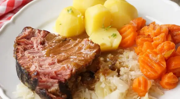 Saftiger Kassler im Ofen mit Salzkartoffeln, Möhren und Sauerkraut. Ein deftiges Gericht, das auf der Zunge zergeht.