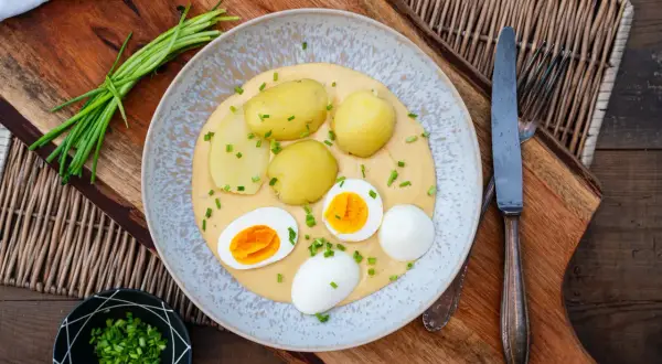 Klassische eier rezepte: gekochte Eier mit Kartoffeln und einer cremigen Sauce, garniert mit Schnittlauch.