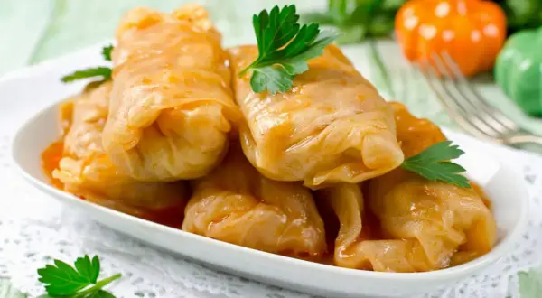 Kohlrouladen mit Hackfleisch in Sauce auf einem Teller, garniert mit Petersilie.