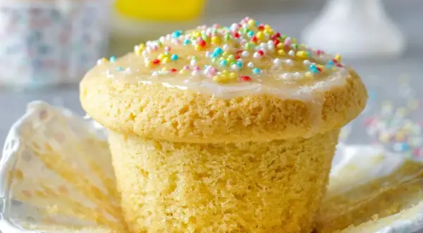 Ein leckerer Muffin mit Zuckerguss und bunten Streuseln, perfekt für einen Kindergeburtstag.