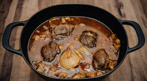 Herzhafte schmorgerichte im gusseisentopf, mit zarten Fleischröllchen und aromatischem Gemüse, köcheln in einer tiefen, dunklen Sauce.