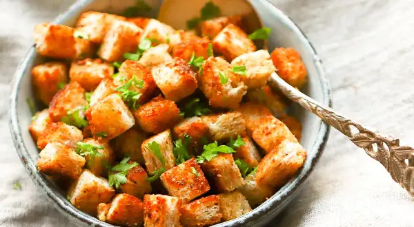 Goldbraune, knusprige Croutons mit Petersilie garniert, perfekt zum Salat. So einfach kannst du Croutons selber machen!