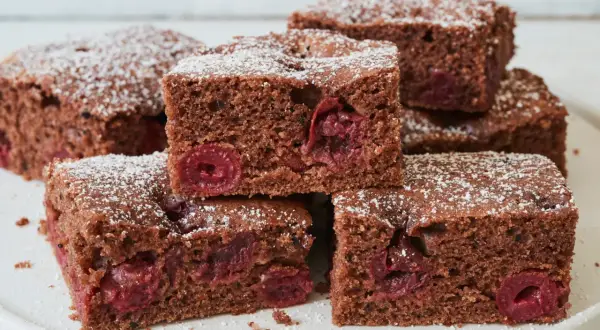 Saftiger Schokokuchen vom Blech mit Kirschen, bestäubt mit Puderzucker. Ein Genuss für jeden Schokoladenliebhaber.