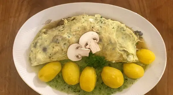 Ein Omelett mit Pilzen, serviert mit kleinen Kartoffeln und grüner Sauce. Perfekt für Pilz-Rezepte!