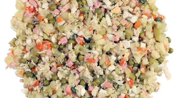 Ein Olivier Salat mit Kartoffeln, Erbsen, Karotten, Ei und Schinken. Perfekt für ein Picknick oder als Beilage.