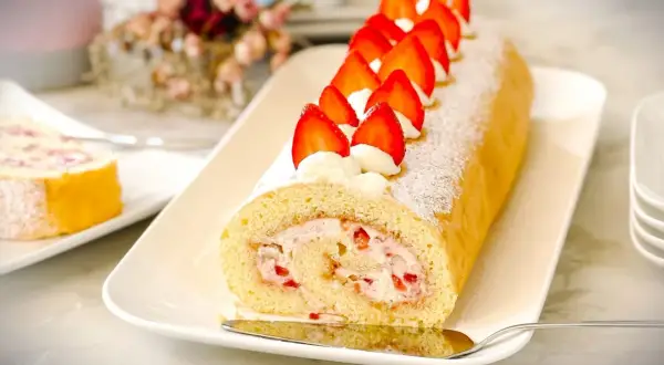 Ein köstliches Biskuitrolle Rezept mit frischen Erdbeeren und Sahne, bestäubt mit Puderzucker. Perfekt für jeden Anlass!