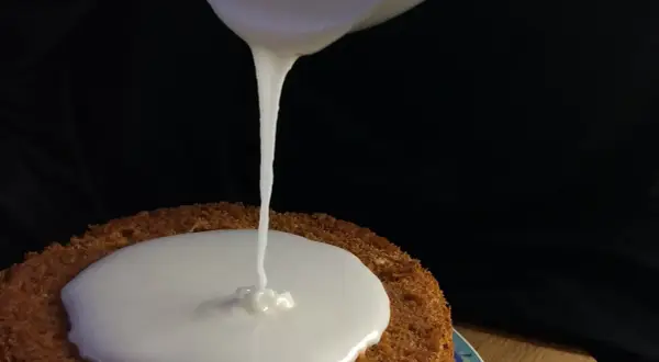 Zuckerguss Rezept: Ein Kuchen wird mit flüssigem Zuckerguss überzogen.