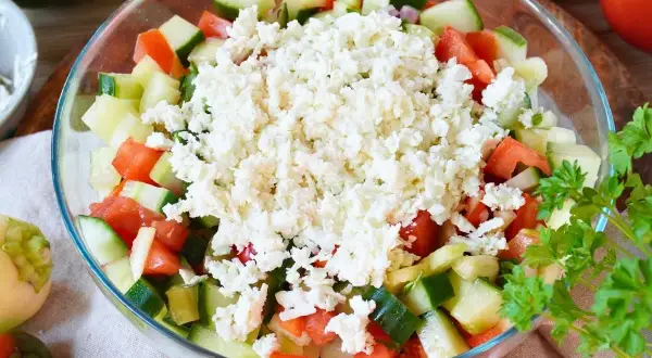 Frischer Schopska Salat mit Gurken, Tomaten und viel zerbröseltem Schafskäse, garniert mit Petersilie.