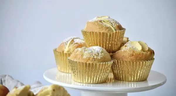 Goldene Apfelmuffins, bestäubt mit Puderzucker, warten auf das apfelmuffins rezept.