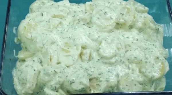 Cremiger Kartoffelsalat mit Kräutern und einem Hauch Balsamico, serviert in einer Glasform.