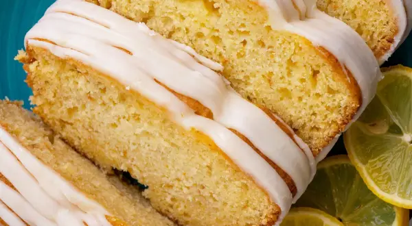 Saftiger zitronenkuchen mit Joghurt, überzogen mit süßer Glasur und garniert mit frischen Zitronenscheiben.