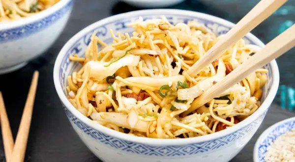Ein Schüsselchen mit friss dich dumm salat, Nudeln, Gemüse und Erdnüssen, bereit zum Genießen mit Stäbchen.