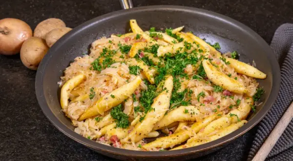Herzhaftes Gericht mit Spätzle und Sauerkraut, garniert mit Petersilie. Ein tolles Sauerkraut Rezept für Genießer.