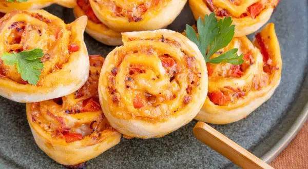 Goldbraune Pizzaschnecken mit Tomaten und Käse, garniert mit Petersilie. Ein leckeres Pizzaschnecken Rezept für jeden Anlass.