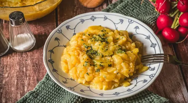 Omas Salate Rezepte: Ein Teller Kartoffelsalat, garniert mit Petersilie, daneben Radieschen und Gewürzstreuer.