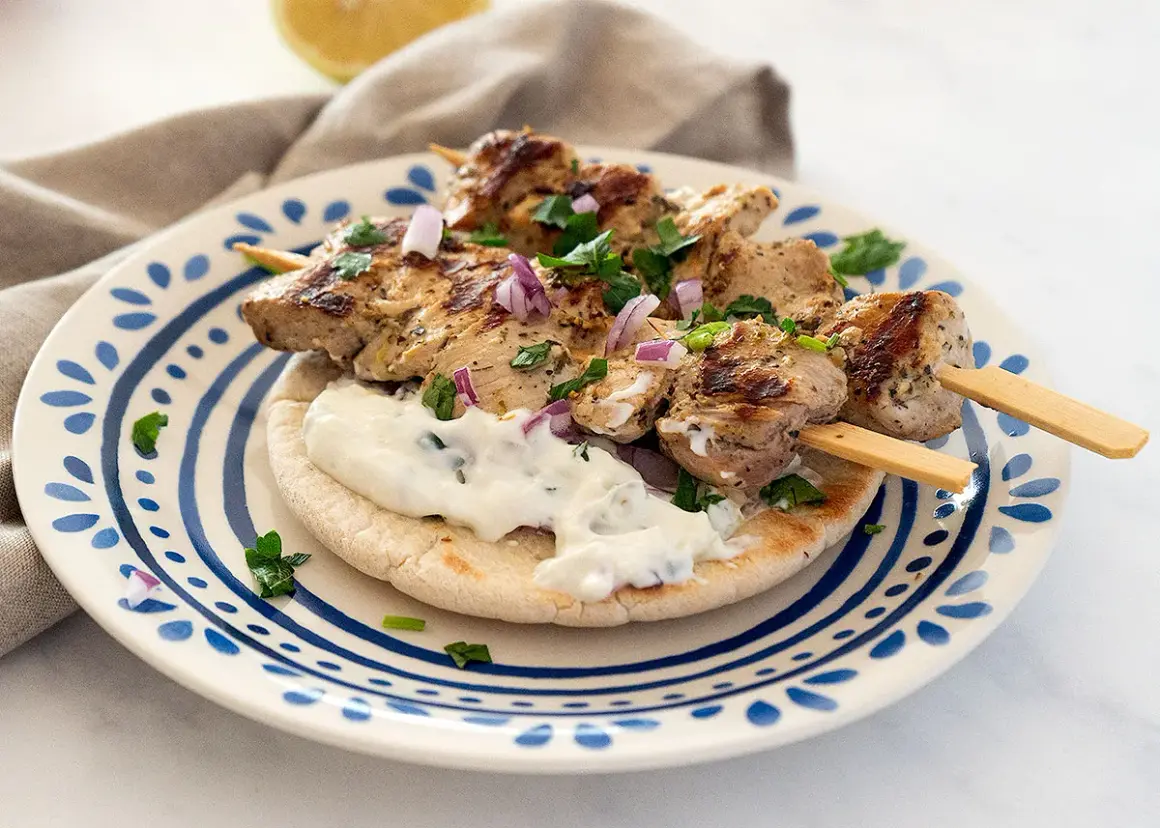Saftige Hähnchen-Souvlaki-Spieße auf Pitabrot mit Tzatziki und roten Zwiebeln. Ein köstliches Souvlaki Rezept für den Sommer.