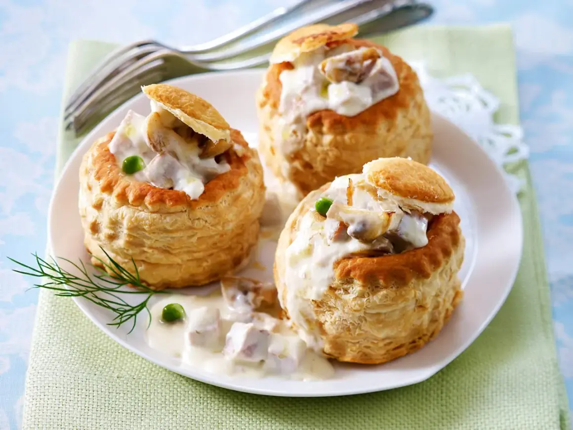 Drei Blätterteig-Schiffchen gefüllt mit cremigem Ragout Fin, garniert mit Erbsen und Dill.