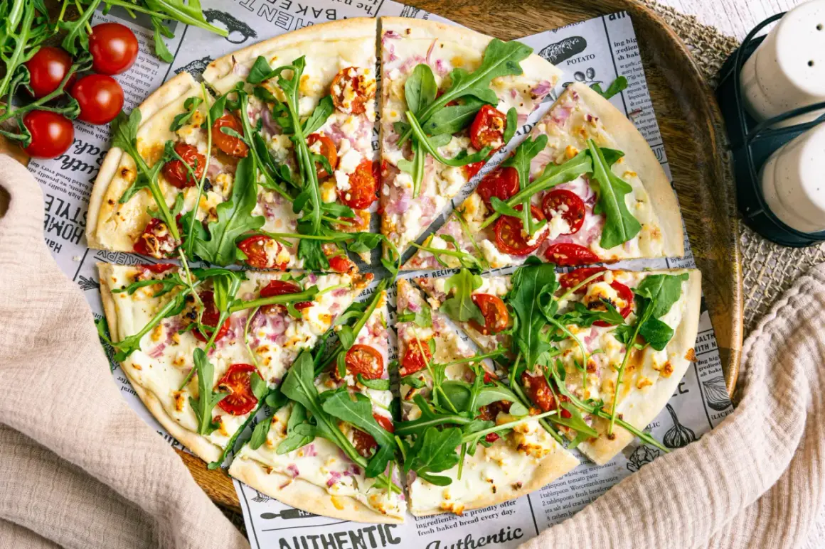 Ein köstlicher flammkuchen vegetarisch mit Kirschtomaten, Rucola und Ziegenkäse auf dünnem Teig.