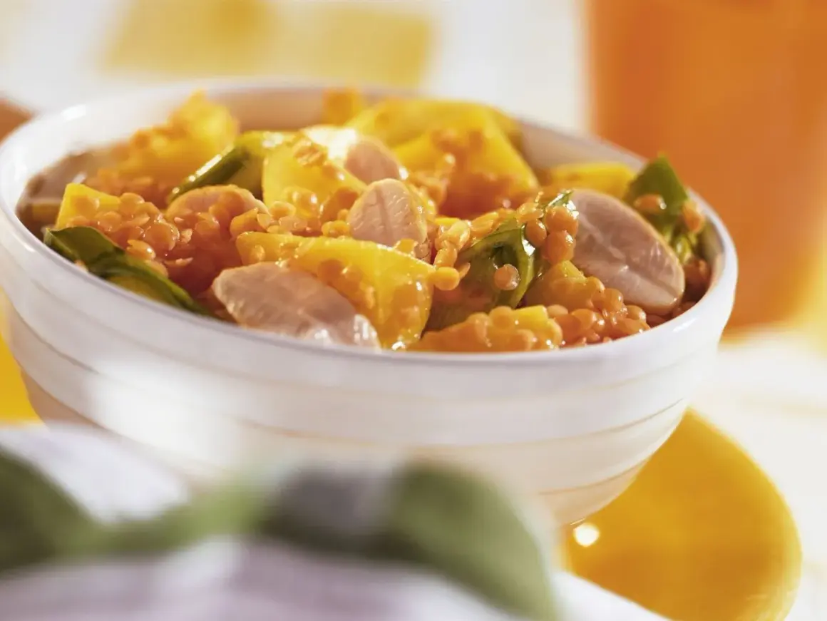 Schüssel mit einem leckeren roten Linsen Rezept, garniert mit gelben Paprikastücken und Fleischstreifen.