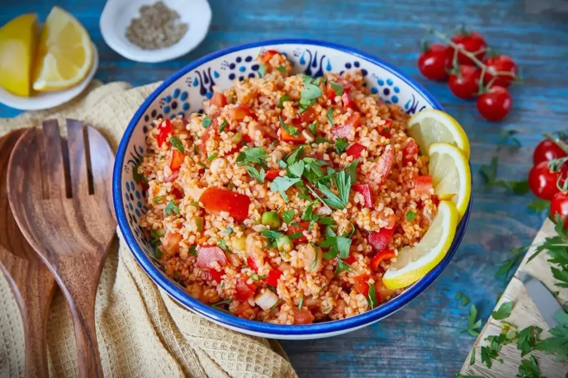 Frischer Bulgur Salat mit Tomaten, Paprika und Kräutern, garniert mit Zitronenspalten. Ein leichter Genuss!