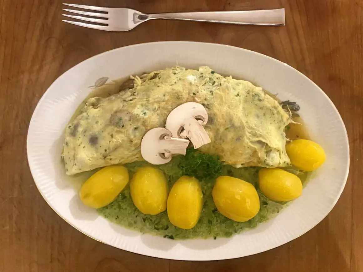 Ein Omelett mit Pilzen, serviert mit kleinen Kartoffeln und grüner Sauce. Perfekt für Pilz-Rezepte!