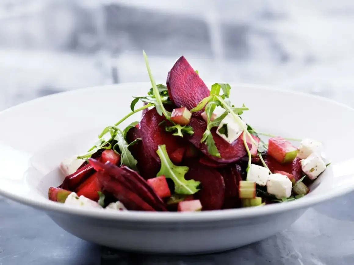 Ein köstlicher rote beete salat mit Rucola, Feta und Apfelstücken in einer weißen Schüssel.