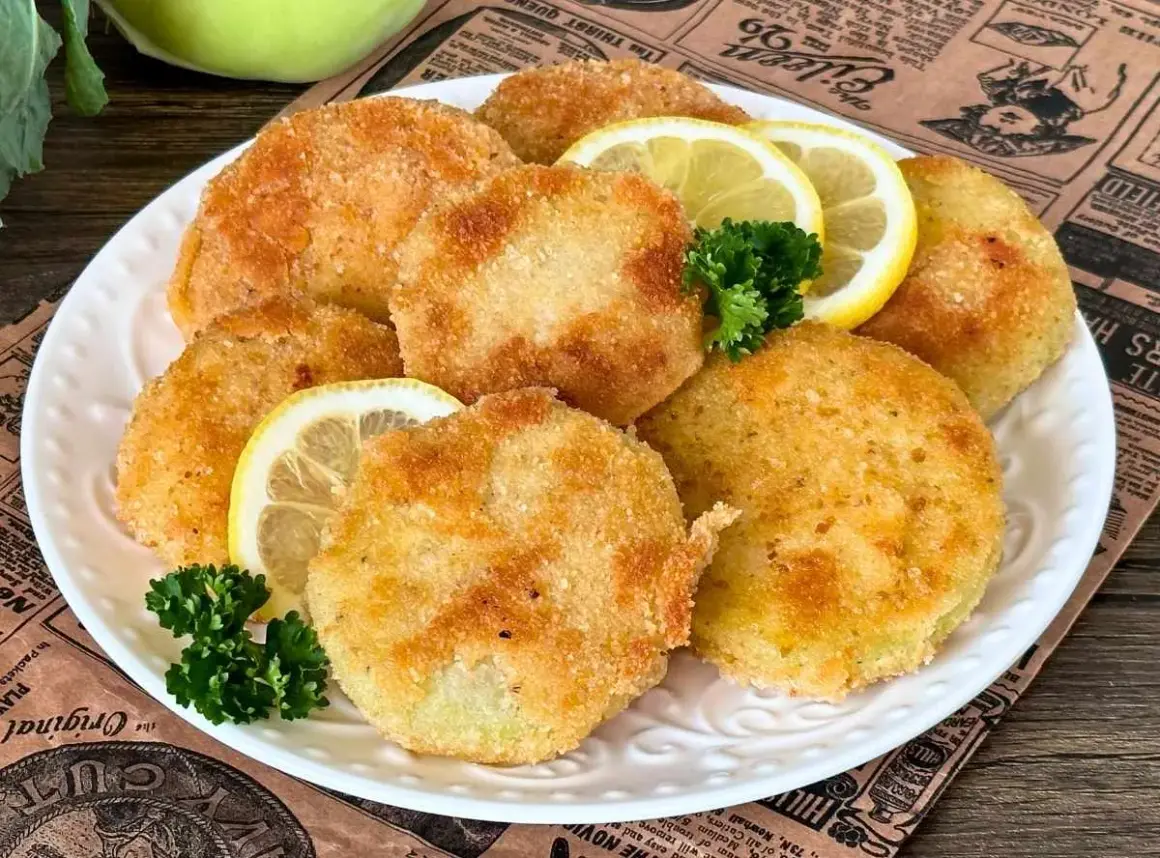 Knusprige Kohlrabi-Schnitzel auf einem Teller mit Zitronenscheiben und Petersilie garniert. Ein köstliches vegetarisches Gericht.