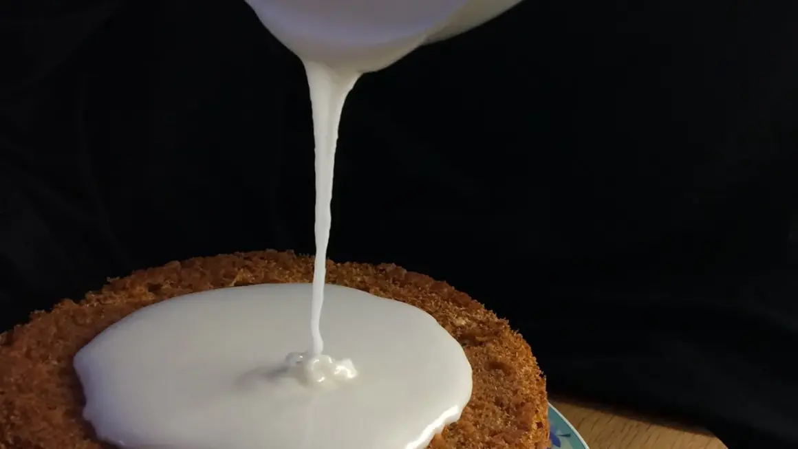 Zuckerguss Rezept: Ein Kuchen wird mit flüssigem Zuckerguss überzogen.