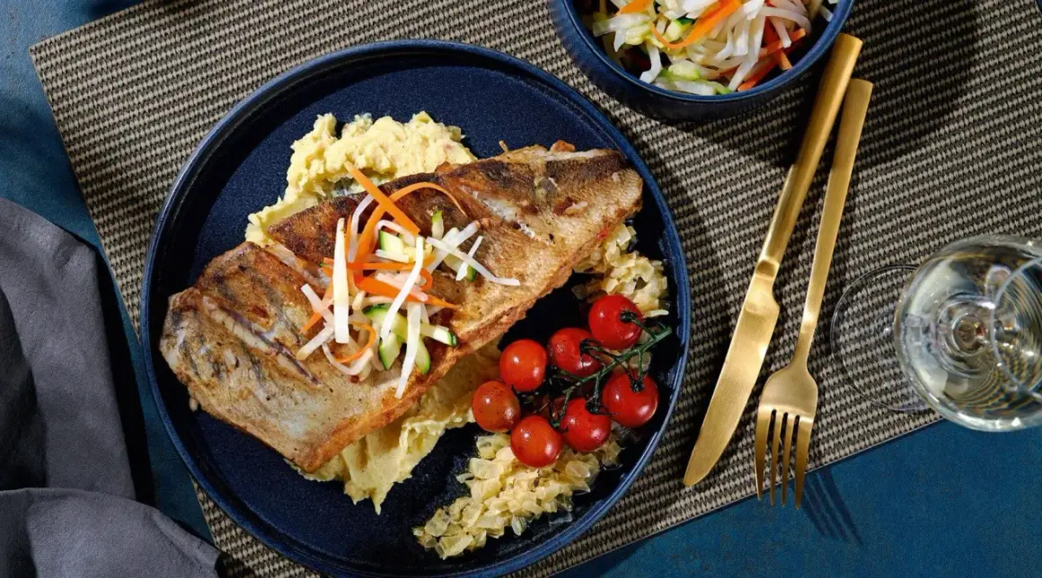 Gebratener Fisch auf Kartoffelpüree mit Kirschtomaten und knackigem Gemüse. Eine köstliche Beilage, die gut zu Kabeljau passt.