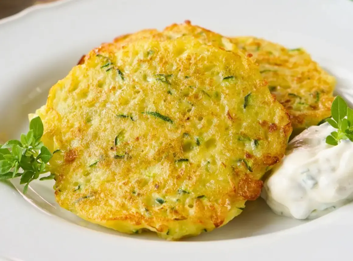 Goldbraune Zucchini-Puffer mit Kräuterquark und frischem Grün.