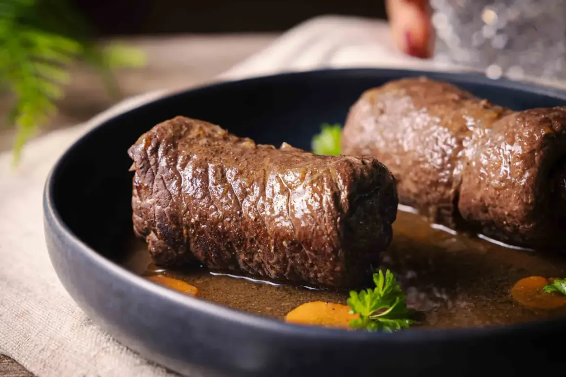 Zwei saftige Rouladen im Schnellkochtopf, serviert mit Karottenstücken und Petersilie in einer dunklen Sauce.