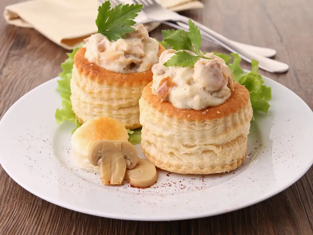 Zwei Bl&auml;tterteig-T&ouml;rtchen gef&uuml;llt mit cremigem Ragout Fin, garniert mit Petersilie und Pilzen.