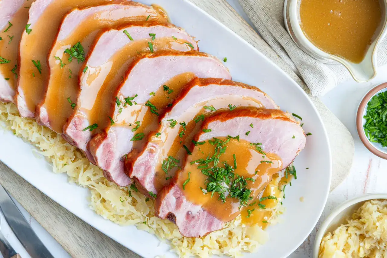 Saftiger Kassler im Ofen, auf Sauerkraut serviert und mit einer k&ouml;stlichen Bratenso&szlig;e &uuml;bergossen. Garniert mit frischer Petersilie.