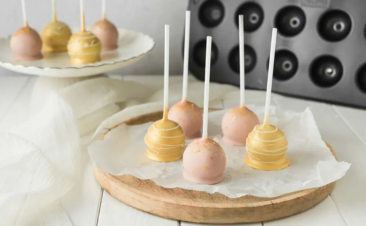 Zarte rosa und goldene cake pops, verziert mit Glitzer und feinen Linien, warten auf ihre Liebhaber.