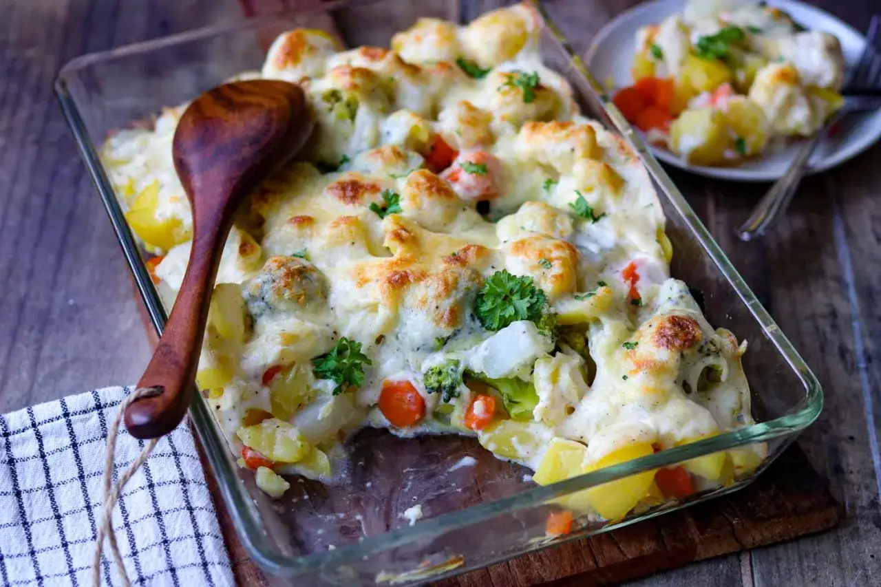 Ein köstlicher vegetarischer Auflauf mit Kartoffeln, Brokkoli, Blumenkohl und Karotten, überbacken mit geschmolzenem Käse.