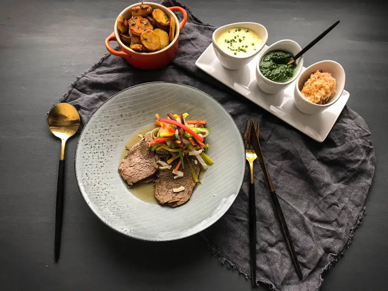 Ein köstliches Tafelspitz-Rezept mit Beilagen: zarte Fleischscheiben, bunte Gemüsestreifen, Bratkartoffeln und drei Saucen.
