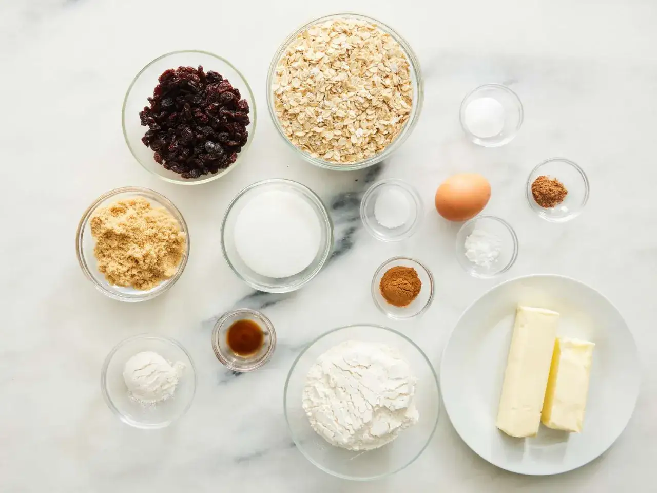 Zutaten für leckere Haferflocken Kekse: Haferflocken, Rosinen, brauner Zucker, weißer Zucker, Mehl, Ei, Butter, Vanille, Zimt, Muskatnuss und Backpulver.