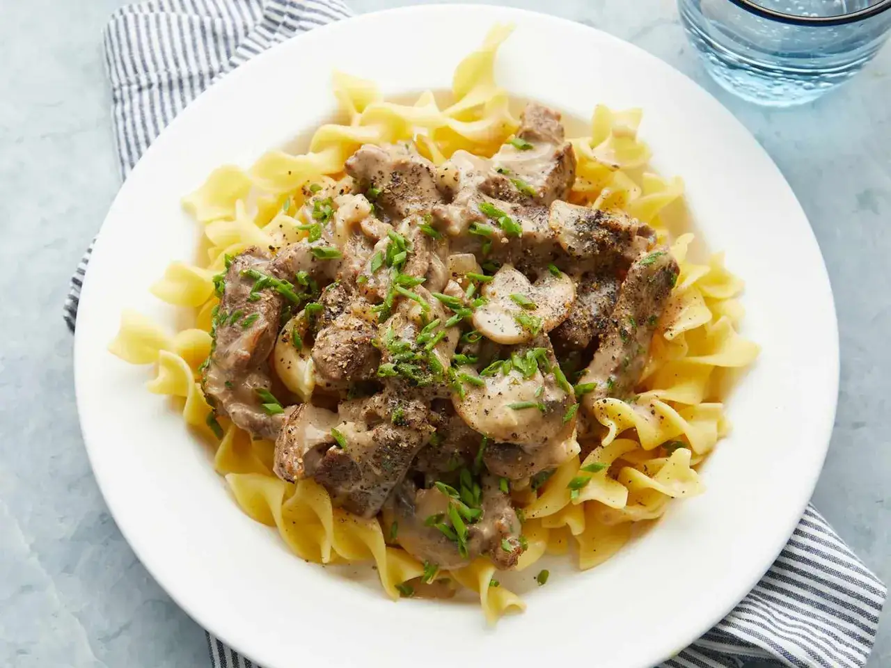 Ein Teller mit Bandnudeln und cremigem Rindfleisch, Pilzen und Kr&auml;utern. Ein k&ouml;stliches Boeuf Stroganoff Rezept.
