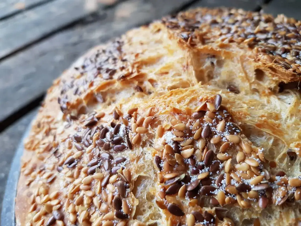 Ein knuspriges Dinkelbrot mit Leinsamen, das auf einem rustikalen Holztisch liegt.