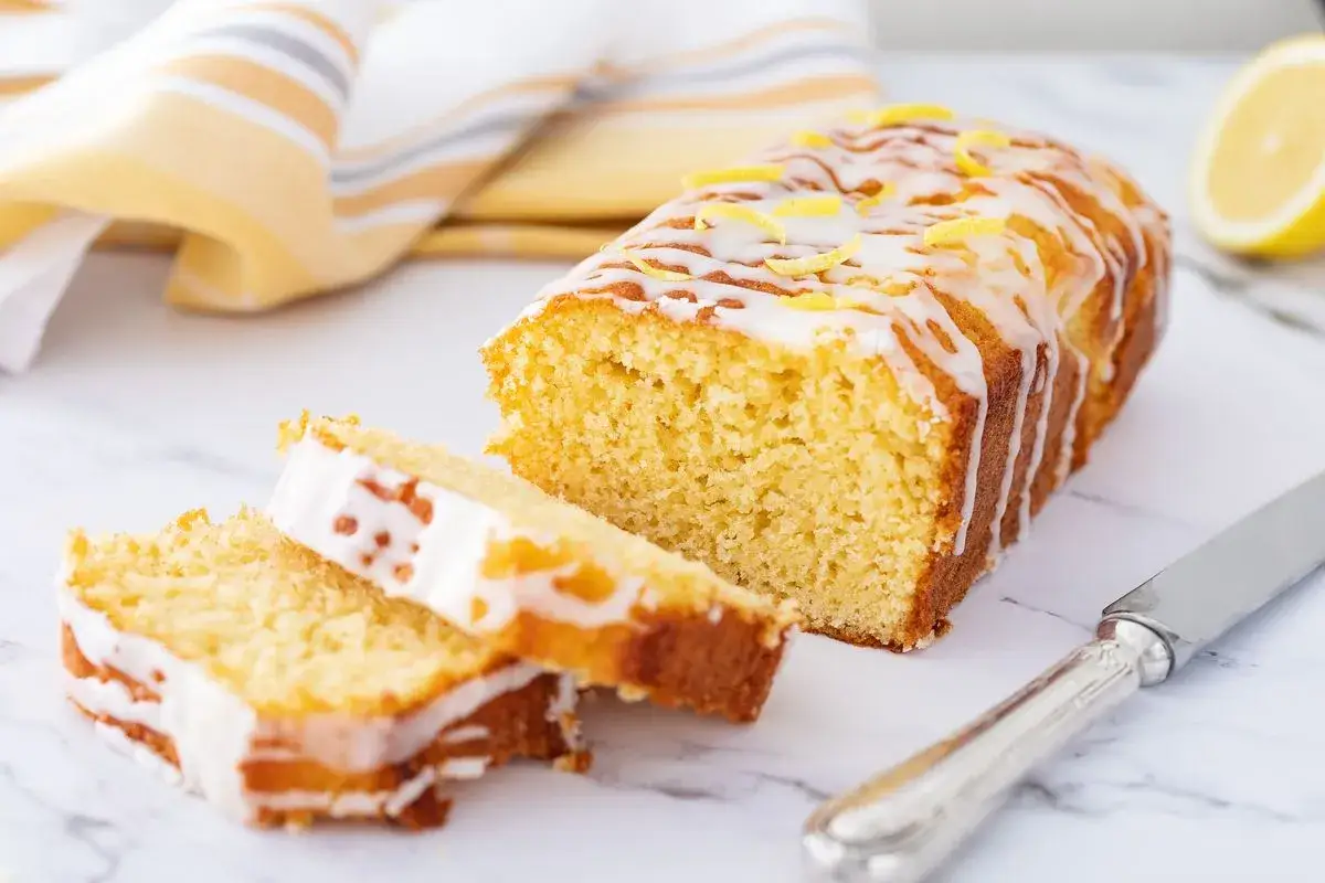 Saftiger zitronenkuchen mit Joghurt, überzogen mit Zuckerguss und garniert mit Zitronenschale. Perfekt für den Nachmittagskaffee.